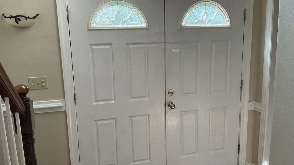 Interior view of white double doors with arched glass windows above