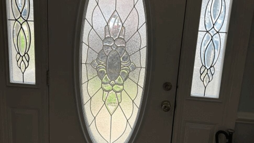 Interior view of white front door with oval decorative glass and two sidelights