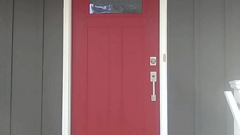 Red steel entry door with rectangular privacy glass, white frame, and modern hardware