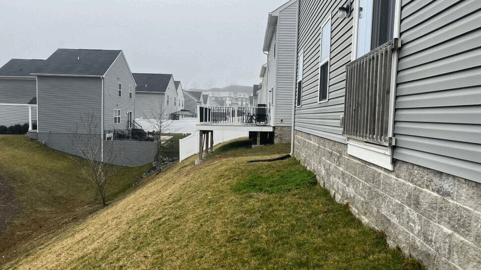 Side view of elevated deck over sloping yard with white rail and black balusters