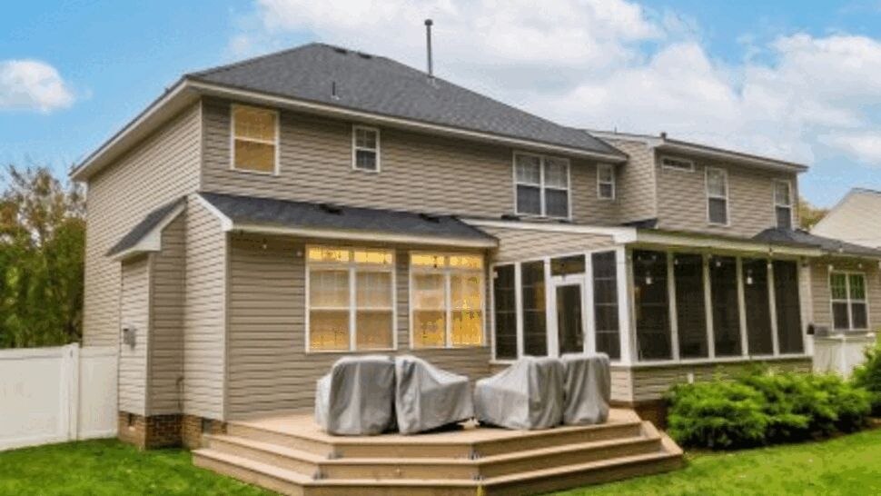 Gray-sided home with rear deck, screened porch, windows, and shingle roof