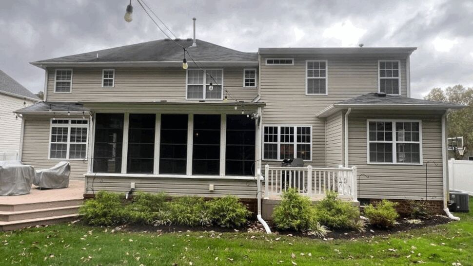 Gray-sided home with screened porch, deck railing, windows, gutters, and downspout