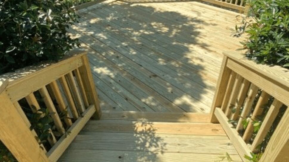 Sunlit Treated Lumber Deck | Exterior Source Virginia Sunlit treated lumber deck with stairs and wood baluster railings in a backyard