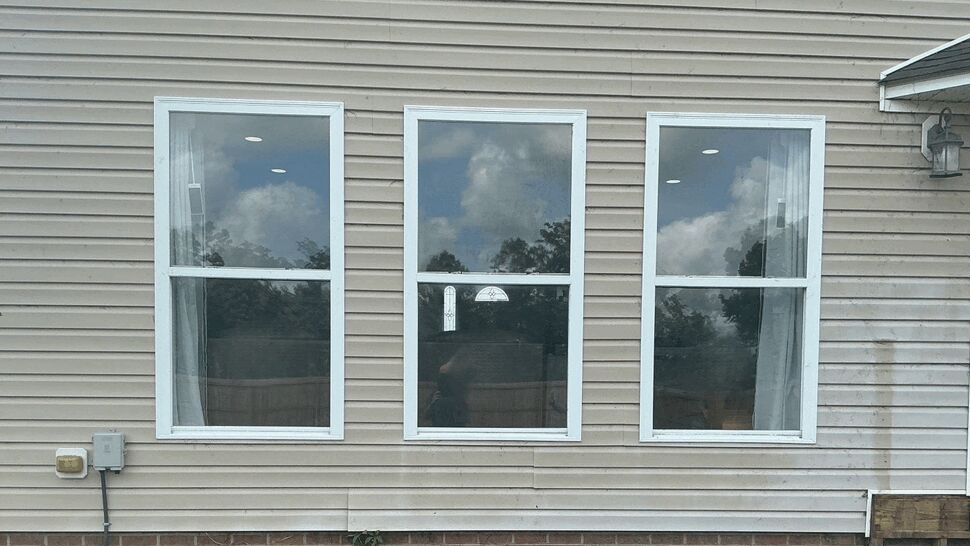 Triple large windows installation | Exterior Source Virginia Three large single-hung windows in a row on beige vinyl siding reflecting sky