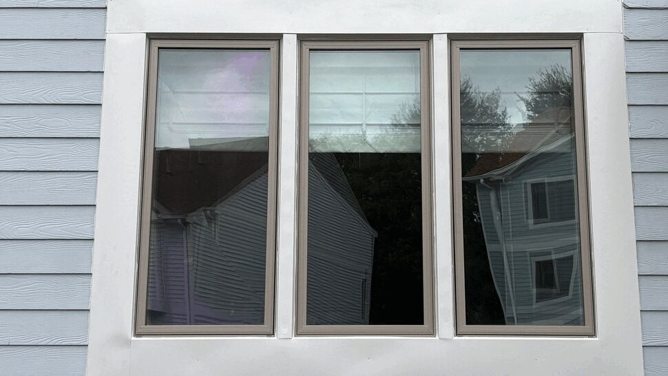 Three-panel window set with white trim on blue siding