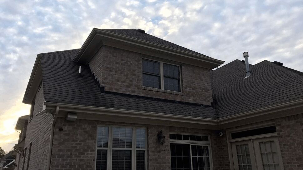 Two-story brick home showing roofline, gutters, and windows at dusk