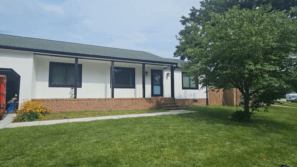 Front view of house with white board-and-batten siding and black trim around windows and porch.