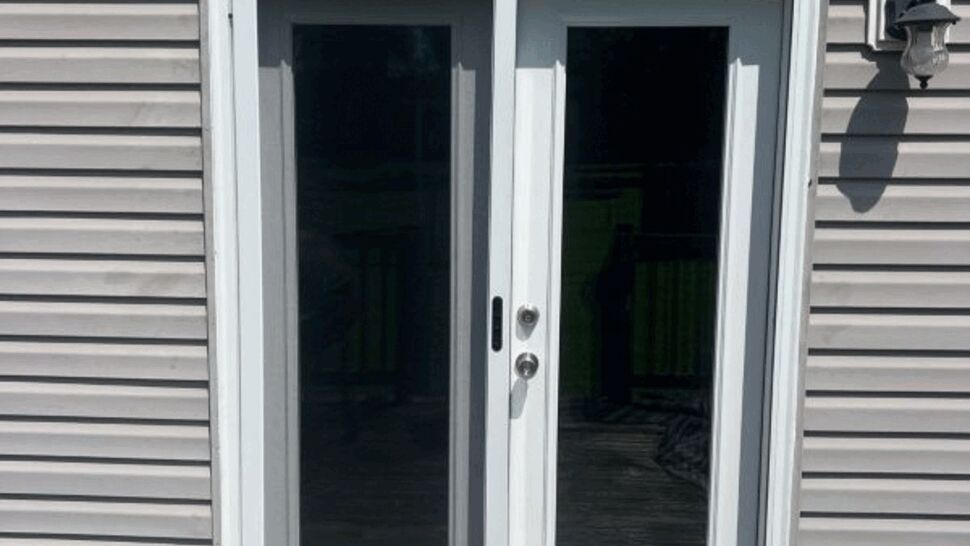 White exterior double glass patio doors with vinyl siding and weathered deck