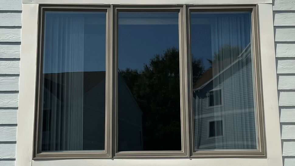 Wide three-panel replacement window with dark frames