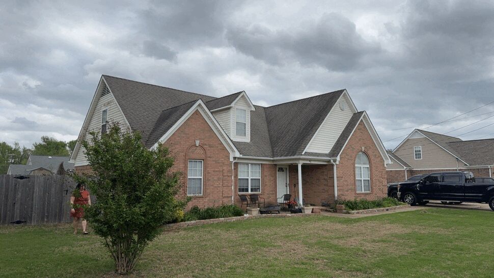 Brick home with pitched roof and cloudy sky over front yard