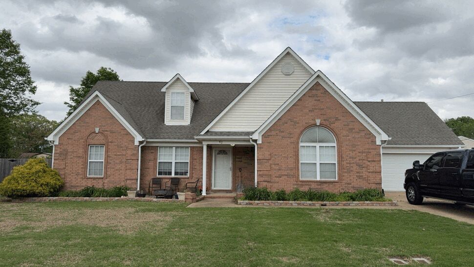 Front view of brick house with porch, arched window and driveway