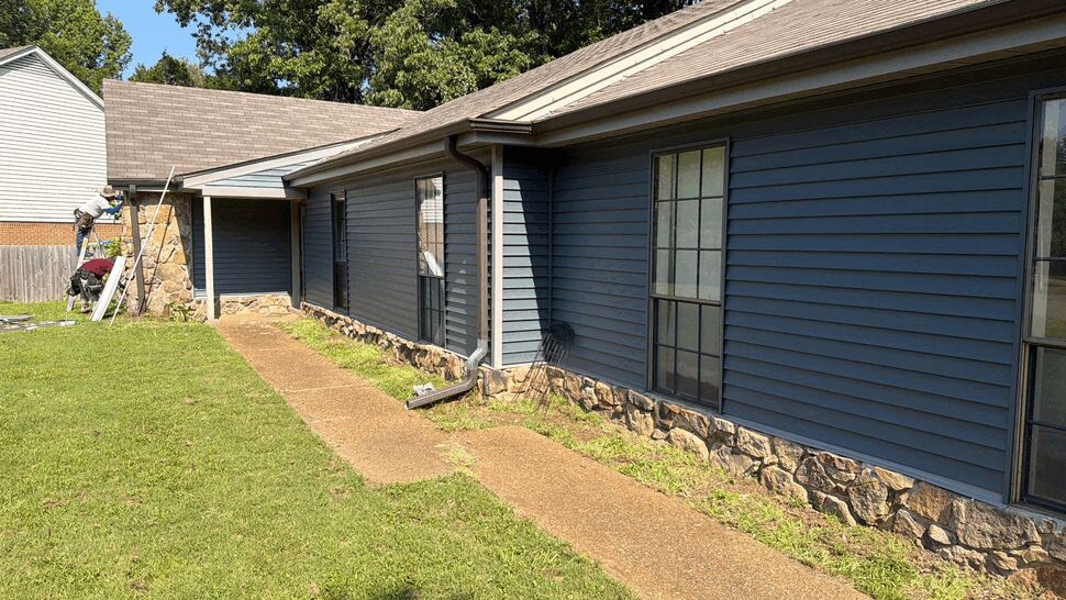 Crew installing siding near front walkway and stone column