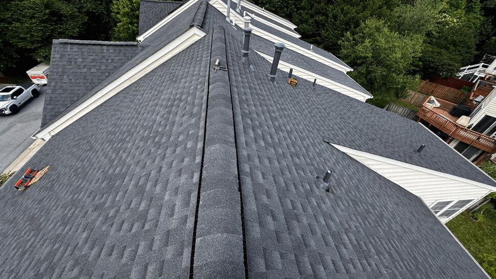 Aerial view of gray asphalt shingle roof with ridge vent and plumbing vents