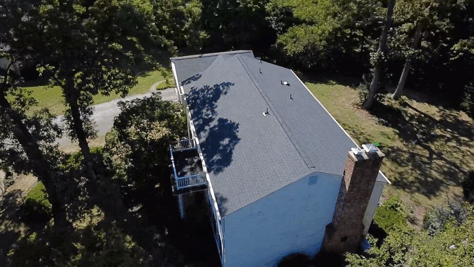 Aerial Gray Roof | Wells Home Improvements Aerial view of a gray shingle roof surrounded by mature trees.