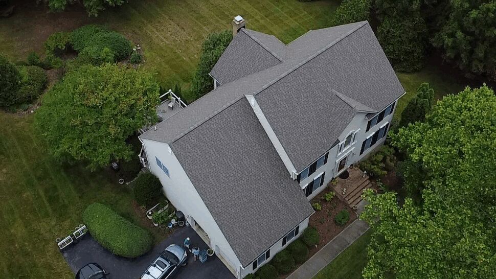 Drone view of grey shingled roof on a two-story suburban home