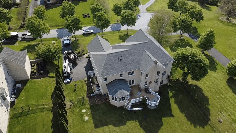 Home Roof and Rear Deck | Wells Home Improvements Aerial view of a gray roof, landscaped yard, and rear deck on a large home.
