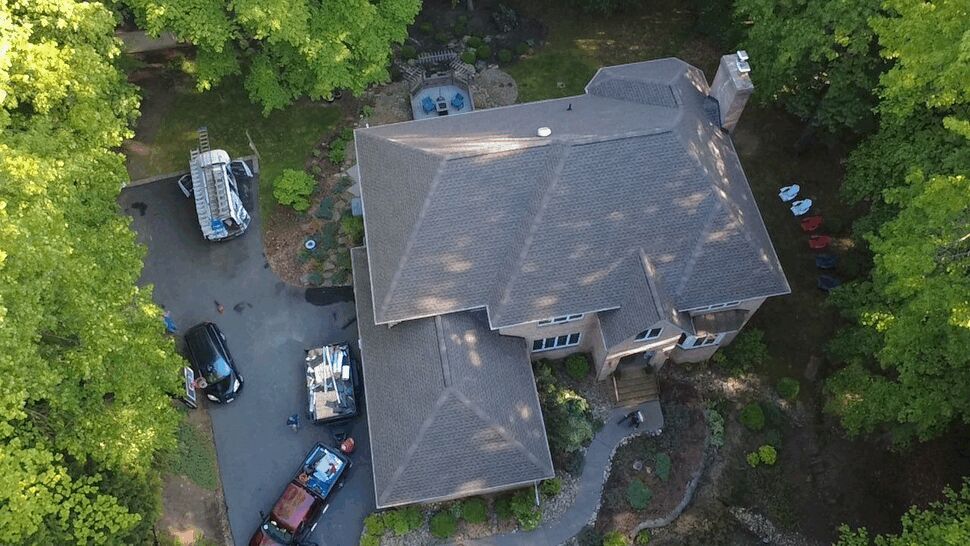 Aerial Home Roof View | Wells Home Improvements Aerial view of a large shingle-roofed home surrounded by trees.