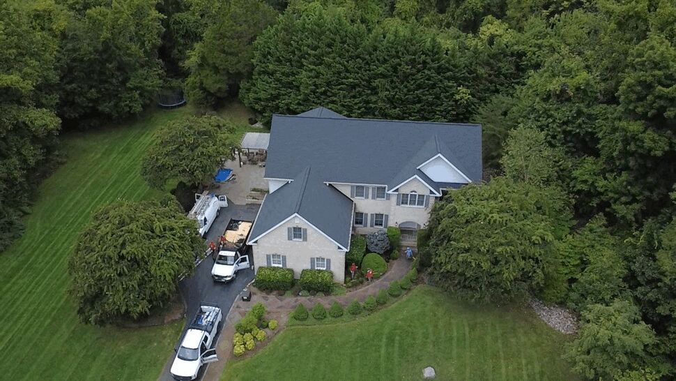 Aerial Residential Roof Overview | Wells Home Improvements Aerial view of a large home with a dark multi-section roof surrounded by trees.