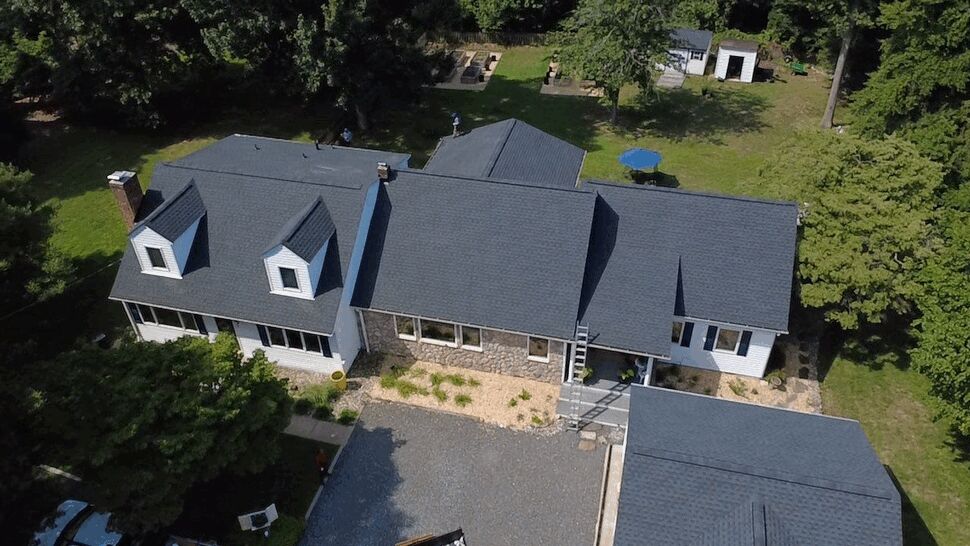 Aerial Residential Roof View | Wells Home Improvements Aerial view of a multi-section house roof with dark new shingles and surrounding trees