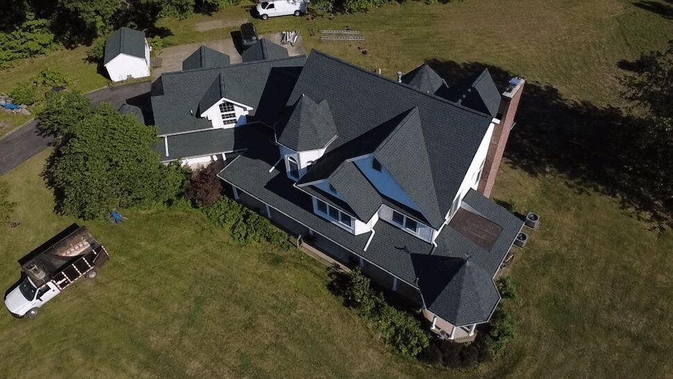 Angled Roof Inspection Shot | Wells Home Improvements Angled aerial view of a multi-gable roof with a work truck nearby on the driveway.