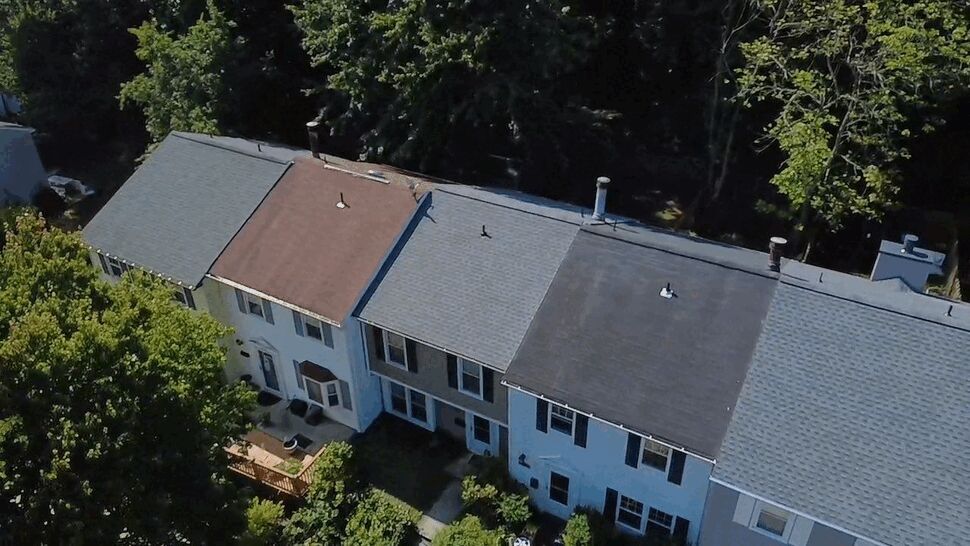 Aerial Rowhouse Roofline Overview | Wells Home Improvements Overhead aerial view of a row of townhouse rooftops and nearby trees.
