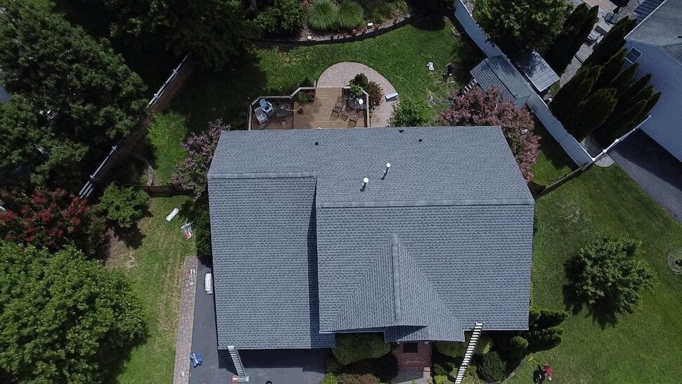 Aerial top-down roof and backyard | Wells Home Improvements Aerial top-down view of an entire gray shingled roof and backyard patio
