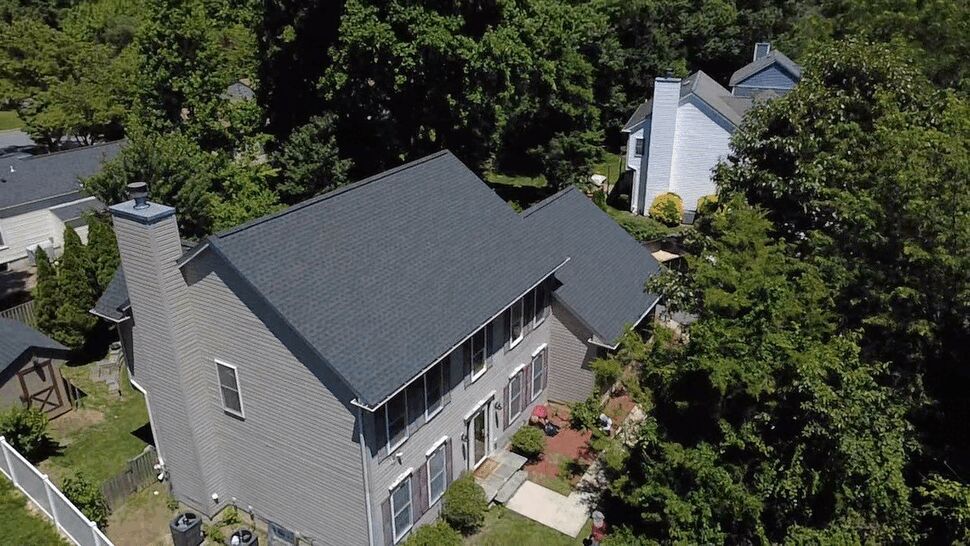 Aerial view of two-story shingled roof | Wells Home Improvements Aerial view of a two-story home with dark shingle roof and surrounding trees