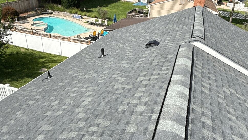Aerial view of shingled roof overlooking backyard pool and trees