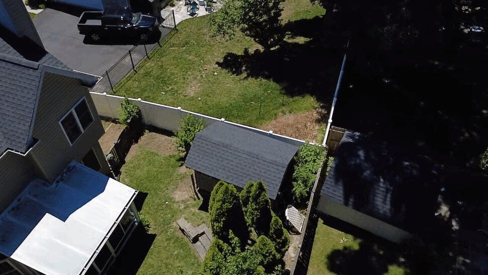 Backyard shed with new shingles | Wells Home Improvements Backyard shed with newly shingled roof beside a fenced yard