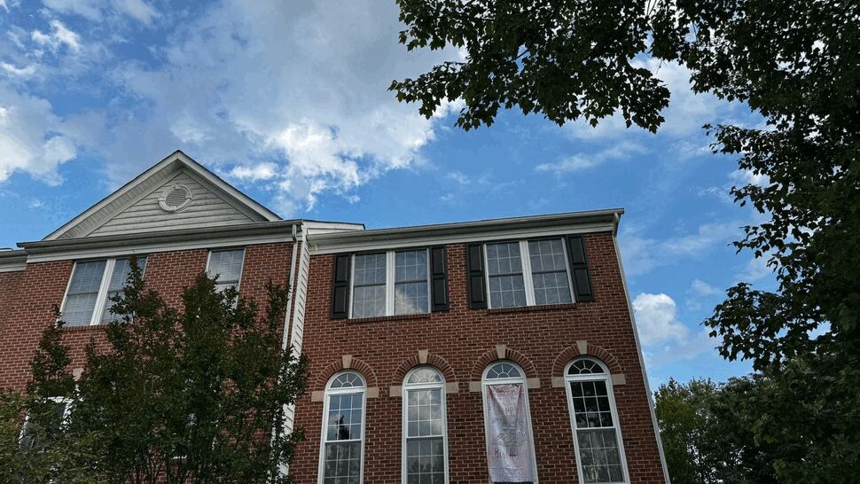 Brick townhouse facade with tall arched windows and gutters