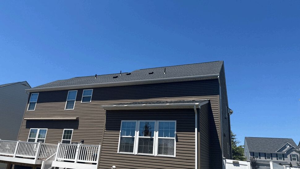 Backyard deck and siding upgrade | Wells Home Improvements Rear view of house with elevated white deck, brown siding, and asphalt shingle roof