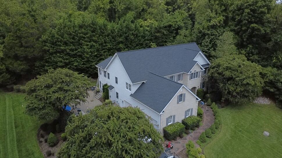 Completed Roof Aerial View | Wells Home Improvements Aerial view of a completed dark roof on a large home surrounded by greenery.