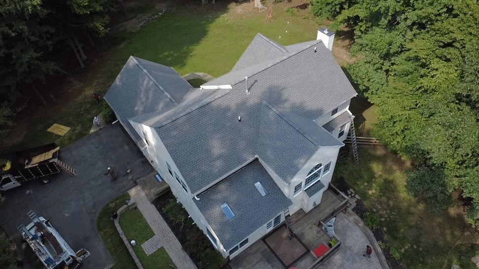 Multi-Gabled Roof and Gutter Inspection | Wells Home Improvements Drone view of a multi-gabled roof and surrounding yard during inspection.