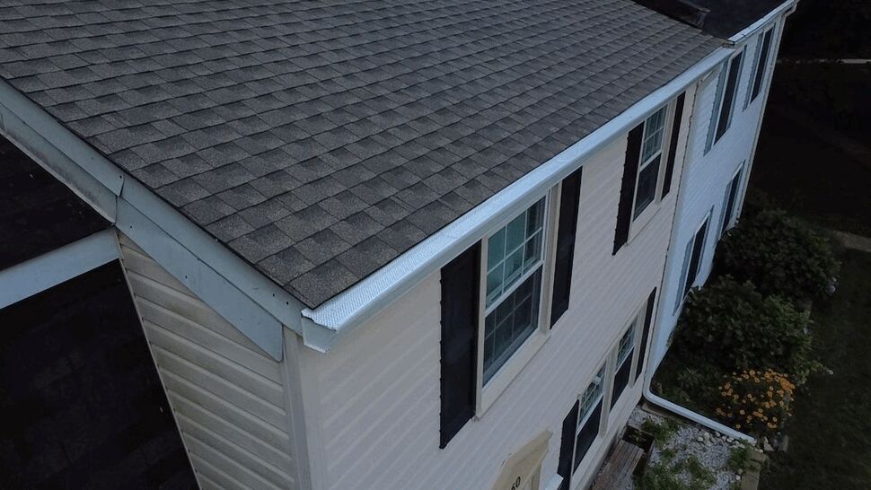 Close-up of white gutter and beige vinyl siding at house corner