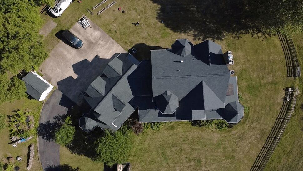 Aerial Roof Top-Down View | Wells Home Improvements Aerial top-down view of a large home's dark shingle roof and surrounding yard.