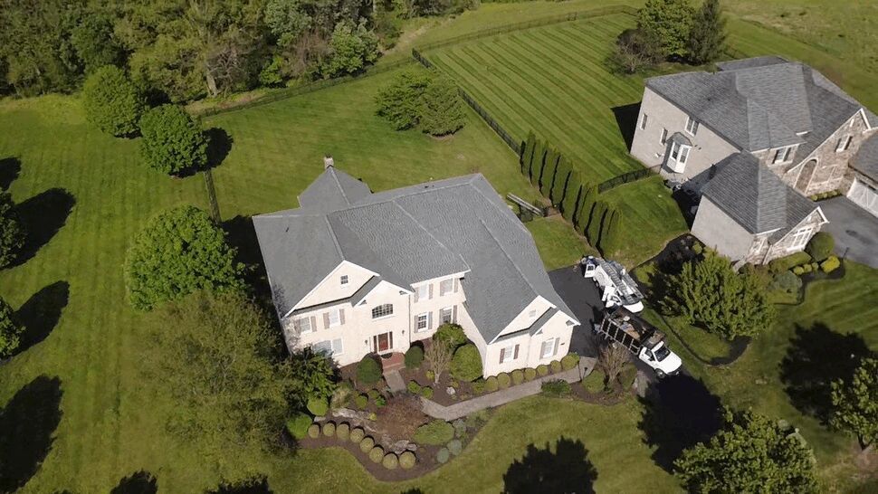 Estate Home Roof Aerial | Wells Home Improvements Aerial view of a large estate home with a gray roof and manicured landscaping.