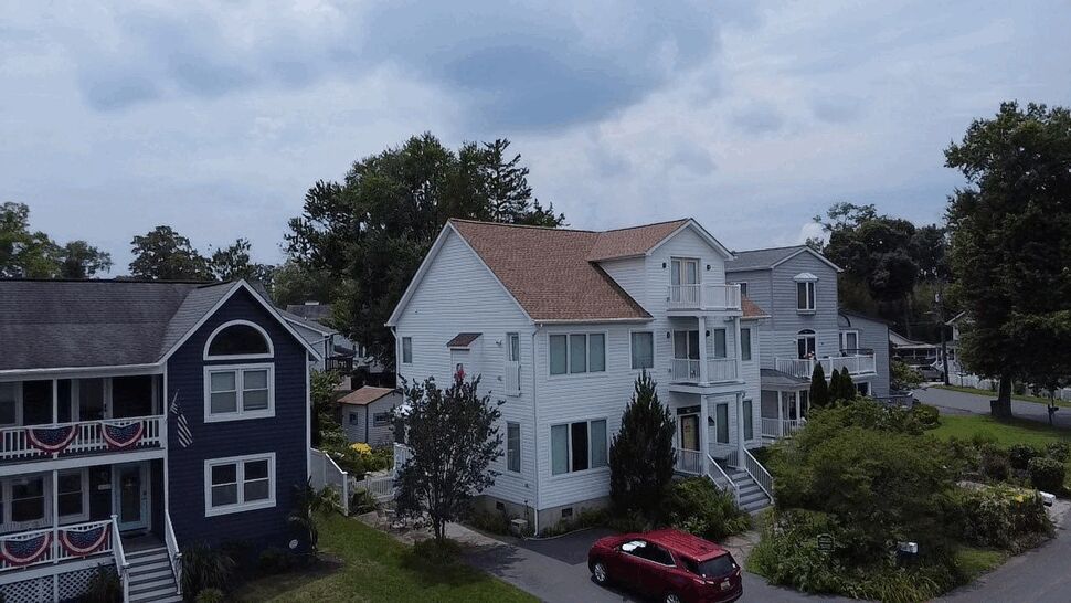 Oblique street view of a house with porch balconies and new windows.