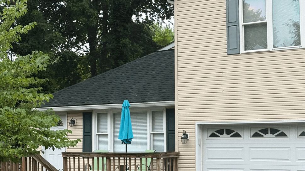 Wooden front deck with blue umbrella beside garage on beige house