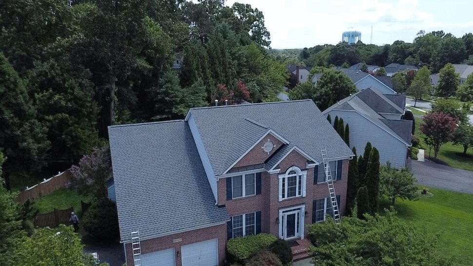 Front view of shingle installation on two-story home | Wells Home Improvements Front elevation of two-story home with new shingles and ladders on roof