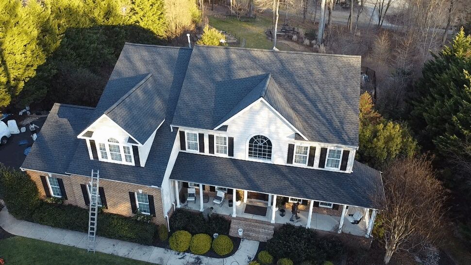 Front Porch Roofing Service | Wells Home Improvements Angled aerial of the front porch and roof with a ladder leaning against the house.