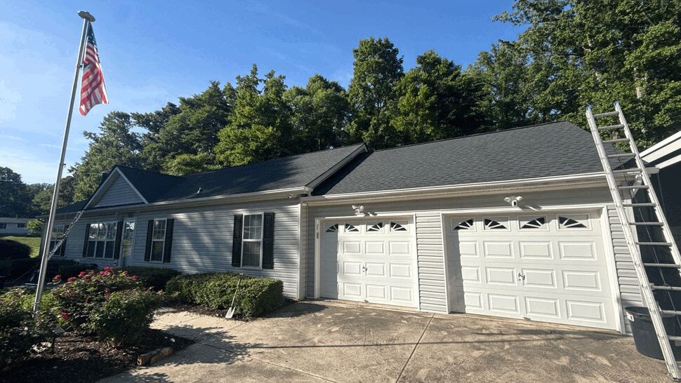 Garage Gutter Service | Wells Home Improvements Garage with double doors, ladder on roof edge, and visible gutters