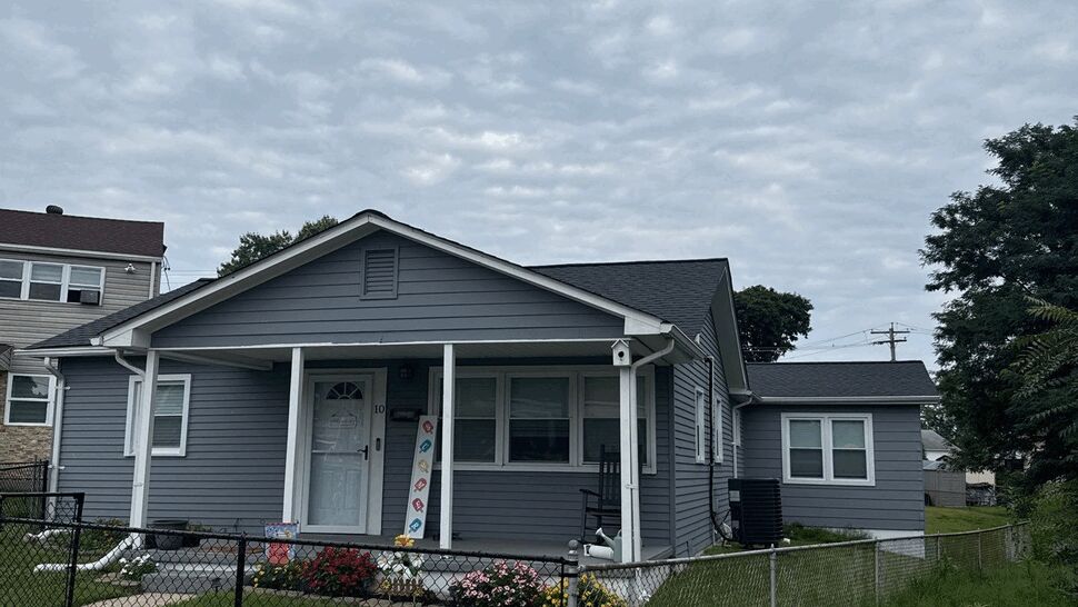 Gray bungalow front siding and porch | Wells Home Improvements Gray bungalow with front porch, fenced yard and flowers