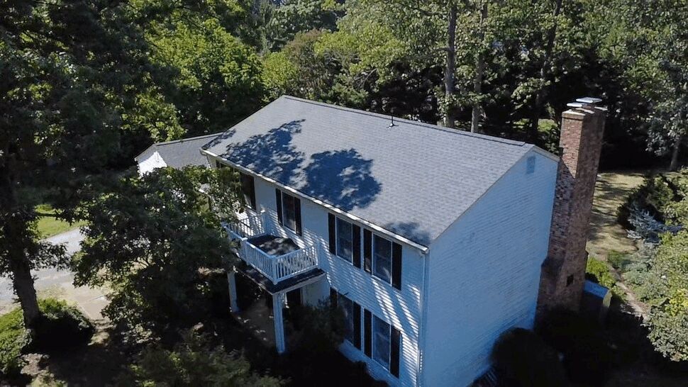 Gray Shingle Roof Home | Wells Home Improvements Gray shingle roof on a white home with a brick chimney and balcony.