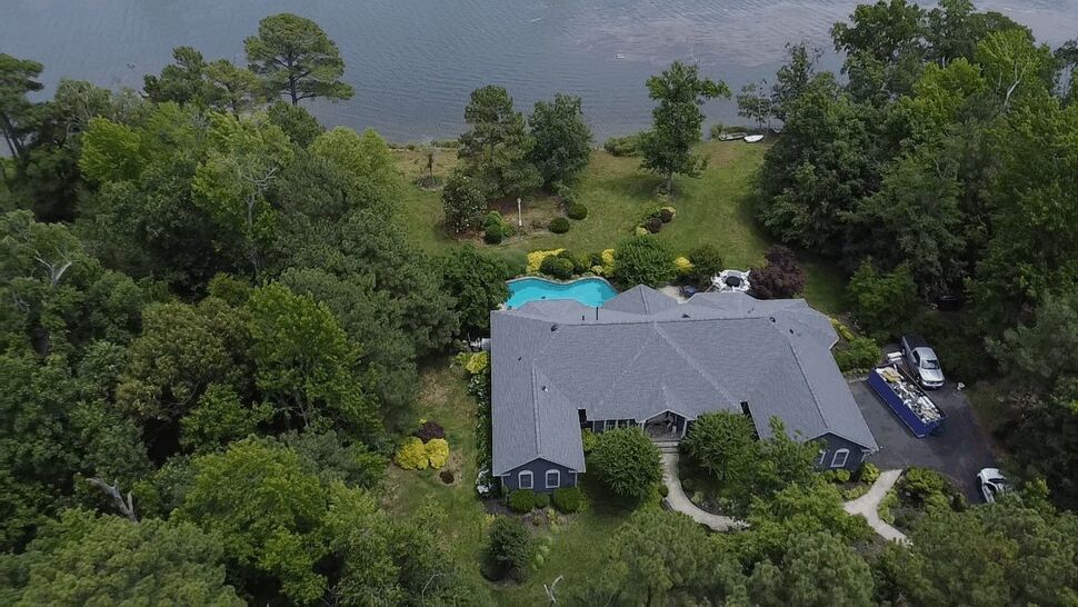 Lakeside Home Roof | Wells Home Improvements Aerial view of a gray shingle roof beside a lake and swimming pool.