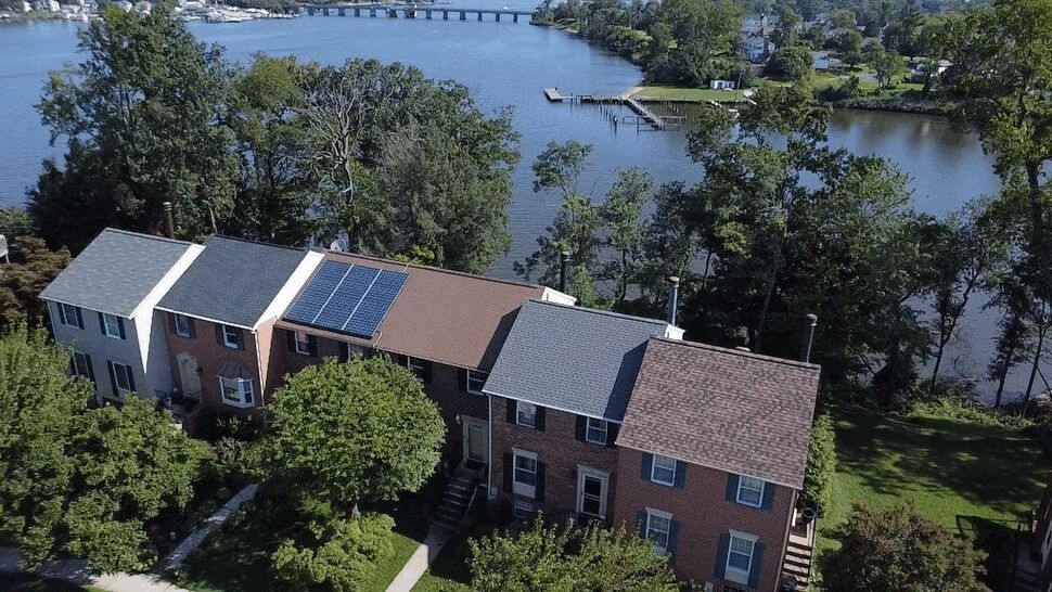 Lakeside Townhouse Roofing | Wells Home Improvements Aerial view of townhouse roofs beside a lake, including solar panels.
