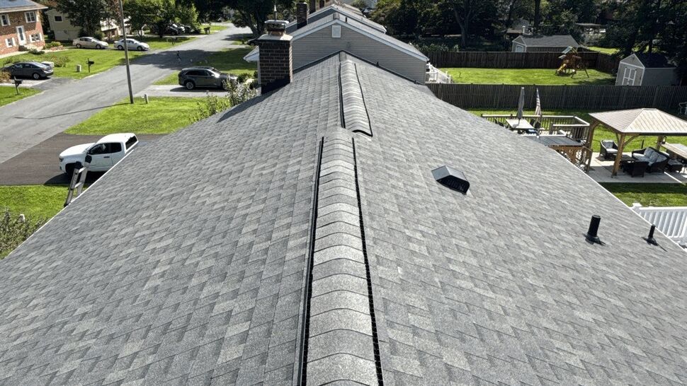Long perspective of a residential gray shingle roof with ridge vent