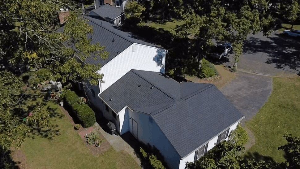Multi-Section Home Roof | Wells Home Improvements Aerial view of a multi-section gray roof on a landscaped home.