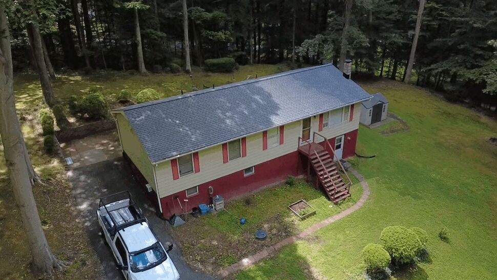 Overhead shot of long roofline and surrounding trees after roof replacement by Wells Home Improvements