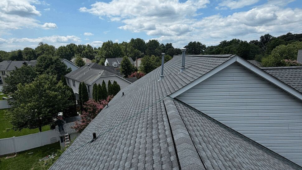 Panoramic shingled roofline over neighborhood | Wells Home Improvements Panoramic view along gray shingled roofline with vents and neighborhood skyline