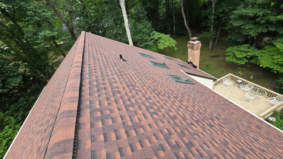 Brown shingle roof with skylights, brick chimney, and adjacent deck